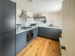 a kitchen with blue cabinets and a wooden floor at Fonseca Cottage in Aberfeldy