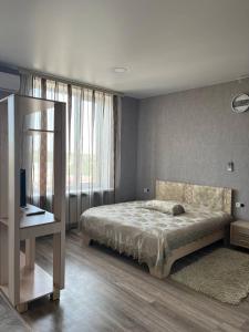 Schlafzimmer mit einem Bett, einem Schreibtisch und einem TV in der Unterkunft Отель Меридиан in Zolotonosha