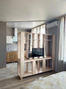 een woonkamer met een bureau en een flatscreen-tv bij Отель Меридиан in Zolotonosha