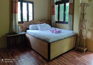 Tiger Land Homestay في Bhurkīā: غرفة نوم بها سرير مع ملاءات بيضاء وورود وردية