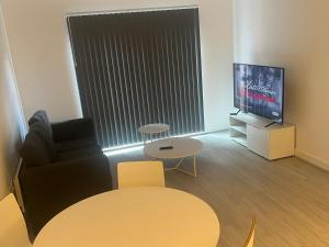 a living room with a chair and a table and a tv at Luxe City Centre in Birmingham