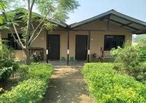 Tiger Land Homestay في Bhurkīā: منزل به شرفة وساحة بها شجيرات