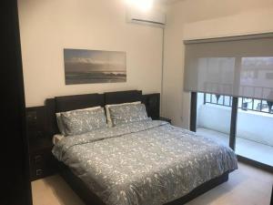 a bedroom with a bed and a large window at Modern two bedroom appartment in Amman