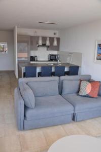 uma sala de estar com um sofá azul e uma cozinha em Magnifique appartement vue mer la turbie em La Turbie