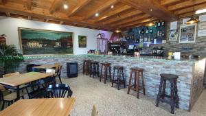 a bar in a restaurant with tables and stools at Pension Parrilla Casa Vicente in Tineo