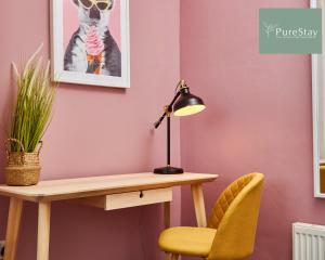 a desk and chair next to a pink wall with a lamp at Fantastic Four Bedroom House By PureStay Short Lets & Serviced Accommodation Leeds With Parking in Headingley