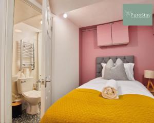 Dormitorio pequeño con cama amarilla y paredes rosas en Fantastic Four Bedroom House By PureStay Short Lets & Serviced Accommodation Leeds With Parking, en Headingley