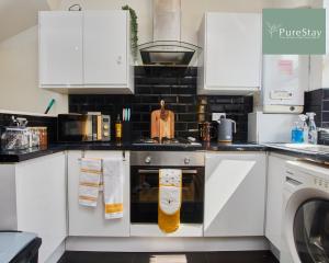 a kitchen with white cabinets and a stove top oven at Fantastic Four Bedroom House By PureStay Short Lets & Serviced Accommodation Leeds With Parking in Headingley