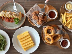 a table topped with plates of food with onion rings and fries at Kokotel Bangkok Dheva Thonglor in Bangkok