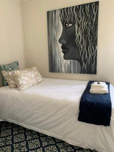 1 dormitorio con 1 cama con una pintura en la pared en The Vine Cottage at Viva Connect, en Cullinan