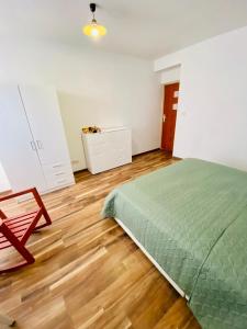 1 dormitorio con cama verde y suelo de madera en Komfortowy pokój dla dwojga z balkonem Marcinkowicka, en Nowy Sącz