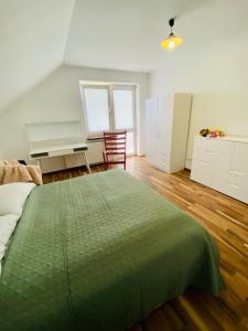 a bedroom with a green bed and a desk at Komfortowy pokój dla dwojga z balkonem Marcinkowicka in Nowy Sącz