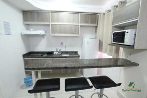 a kitchen with a counter and some stools in it at Lacqua diRoma com Parque Aquático e Cozinha in Caldas Novas