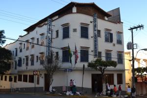 a large white building with people standing outside of it at Hotel Londres in São Lourenço