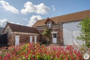 a brick house with a white garage and pink flowers at Gîte du P'tit Colibri in Gury