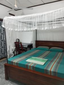 1 dormitorio con cama con dosel y mesa en Dreams Garden Surf Lodge, en Midigama East