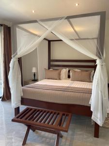 a bedroom with a canopy bed and a wooden bench at Waters Edge Liwonde in Liwonde