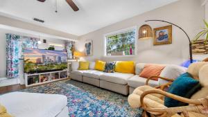 a living room with a couch and a tv at Zen Jungle House by Busch Gardens Sleeps 10 with Outdoor Games and bikes! in Tampa