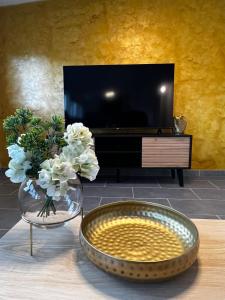 una mesa con un jarrón de flores y una TV en Ferienwohnung Bad Säckingen, en Bad Säckingen