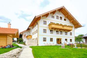 a large white house with a wooden roof at Huberhof Hinzing Ferienbauernhof in Pittenhart