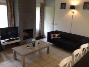 a living room with a black couch and a fireplace at Vakantiehuis Lochem in Lochem