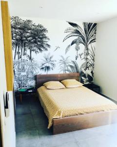 a bedroom with a bed with a mural of palm trees at Villa Ti Alizés in Sainte-Luce