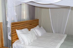 un letto bianco con cuscini bianchi e baldacchino di Dutchess Hotel and Restaurant a Fort Portal