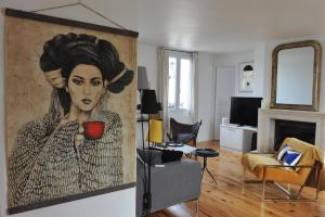 un salon avec un tableau représentant une femme tenant une tasse dans l'établissement L'Appart Gîte de Charme, à Compiègne