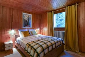 een slaapkamer met een bed en een raam met gele gordijnen bij Chalet des Écureuils - Grand chalet familial proche des pistes avec parking in Courchevel