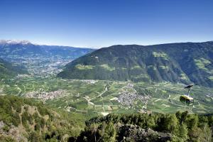 a helicopter flying over a village in a valley at Residence Kronenwirt in Parcines