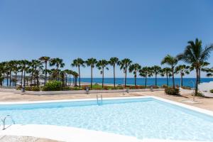 una piscina con la playa al fondo en Bungalow con jardín en Pasito PM40, en Pasito Blanco