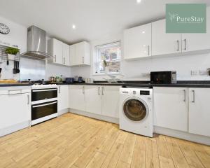 a kitchen with white cabinets and a washing machine at Stunning Two Bed Apartment By PureStay Short Lets & Serviced Accommodation Leamington With Free WiFi in Leamington Spa