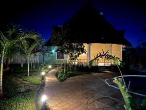 une maison éclairée dans la cour la nuit dans l'établissement Paradiesische Villa Maisha Mazuri mit Pool. Terrasse und Personal, à Diani Beach