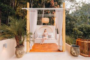 a woman sitting in a swinging bed on a porch at Aobe in Ban Pok Nai