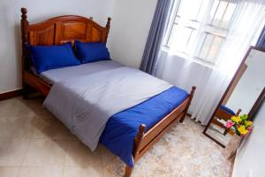 a bedroom with a bed with blue sheets and a window at MANDJ STAYS in Seeta