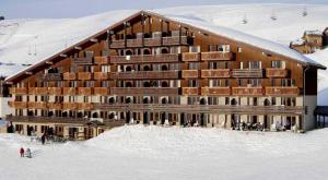 ein großes Gebäude im Schnee mit Leuten davor in der Unterkunft PLAGNE SOLEIL - 5 pers - 4 étoiles Paradiski - vue montagne - accès direct pistes et sentiers in La Plagne Tarentaise