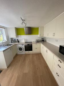 cocina con armarios blancos, lavadora y secadora en Garden flat in 'Little Chelsea', en Eastbourne
