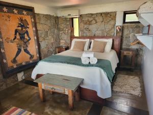 una camera da letto con un letto in un muro di pietra di La Roca House a Praia do Rosa