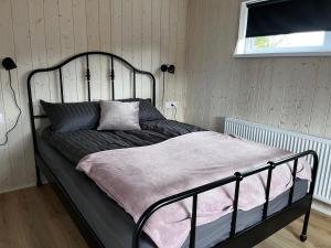 1 cama con marco negro en un dormitorio en Ásólfsstaðir - Miðhóll, en Ásólfsstaðir