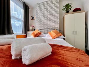 1 dormitorio con 2 camas con almohadas blancas y naranjas en Clarence House 3 Bedrooms 8min to Station E17 North East London, en Londres