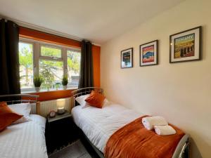 1 dormitorio con 2 camas y ventana en Clarence House 3 Bedrooms 8min to Station E17 North East London, en Londres