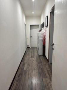 un corridoio con pareti bianche, pavimenti in legno e una porta di Karivi - Poma a Firenze