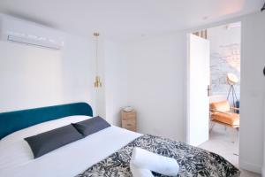 a white bedroom with a bed and a chair at Montmartre Marvel! Renovated Workshop near the Sacré-Coeur Basilica in Paris