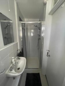 a white bathroom with a shower and a sink at Garden flat in 'Little Chelsea' in Eastbourne