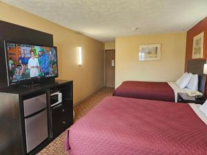 a hotel room with two beds and a flat screen tv at Budgetel inn & Suites in Fort Scott