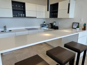 a kitchen with white cabinets and a counter with stools at Moderno y espacioso departamento en Aldea Zama in Tulum