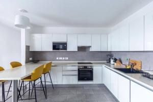 a white kitchen with white cabinets and yellow chairs at Labone Luxury Condo and Apartment in Accra - FiveHills homes in Accra