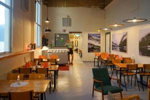 a restaurant with tables and chairs and a person standing in a room at Flørli 4444 Hostel in Fløyrli
