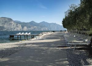 a row of white benches sitting on the beach at Residence Rosemary in Brenzone sul Garda