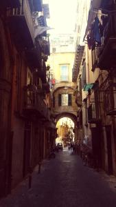 un callejón con un arco entre dos edificios en Napulè, en Nápoles